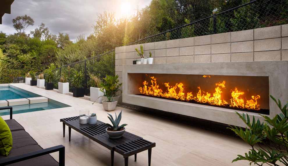 This is an example of a midcentury patio in San Diego with with fireplace, tile and no cover.