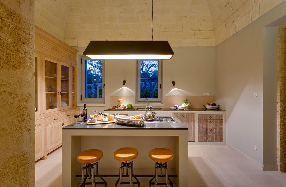 This is an example of a mediterranean galley separate kitchen in Other with raised-panel cabinets, light wood cabinets, stainless steel appliances, with island and beige floor.