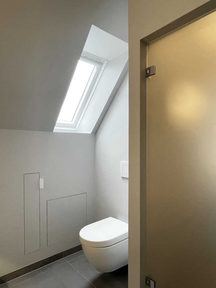 Inspiration for a medium sized contemporary grey and white bathroom in Dusseldorf with flat-panel cabinets, white cabinets, a wall mounted toilet, grey tiles, grey walls, ceramic flooring, a vessel sink, grey floors, a hinged door, grey worktops, a single sink and a freestanding vanity unit.