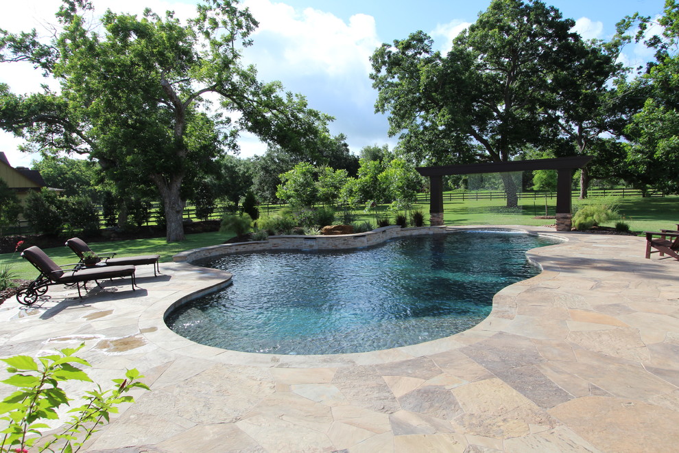 Example of a large mountain style backyard tile and custom-shaped pool fountain design in Houston