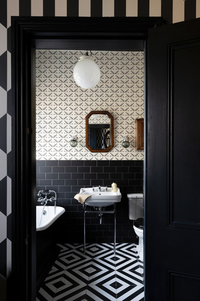 Modelo de cuarto de baño único tradicional con bañera exenta, baldosas y/o azulejos blancas y negros, lavabo tipo consola y suelo negro