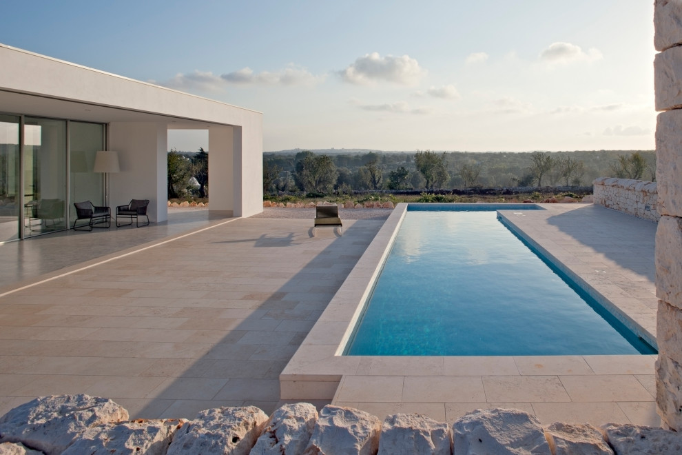 Inspiration for a mid-sized modern courtyard l-shaped aboveground pool in Other with natural stone pavers.