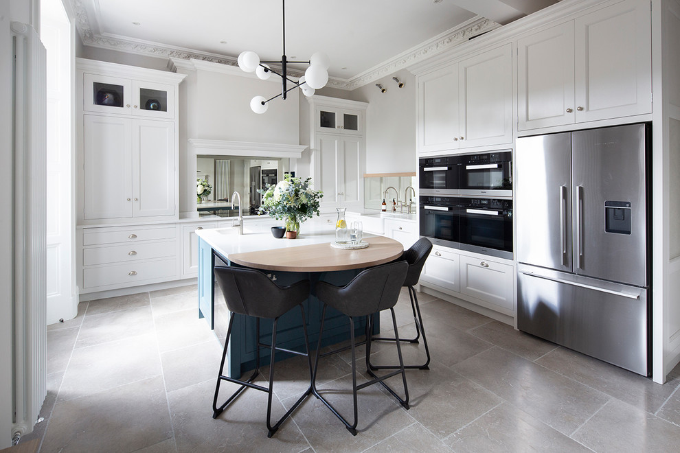 Inspiration for a large eclectic l-shaped eat-in kitchen in Edinburgh with a farmhouse sink, beaded inset cabinets, white cabinets, quartzite benchtops, mirror splashback, stainless steel appliances, with island, beige floor and white benchtop.