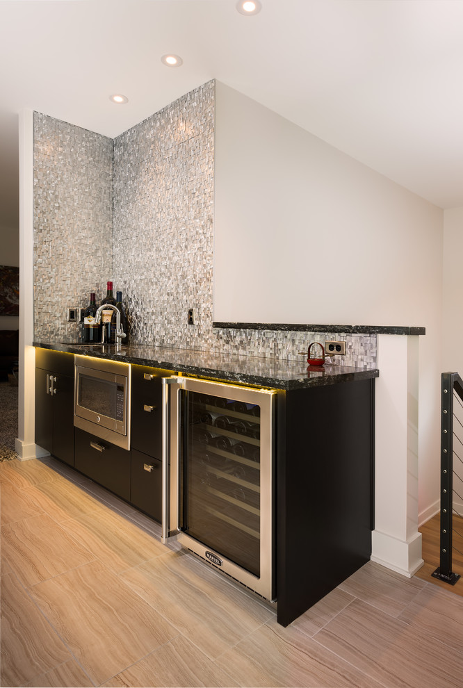 Inspiration for a mid-sized contemporary single-wall wet bar in Miami with an undermount sink, flat-panel cabinets, dark wood cabinets, granite benchtops, grey splashback, metal splashback, porcelain floors, beige floor and black benchtop.