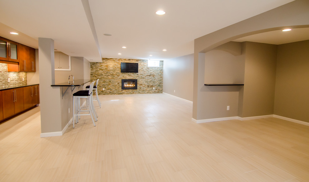 Photo of an expansive contemporary walk-out basement in DC Metro with beige walls, porcelain floors and a stone fireplace surround.