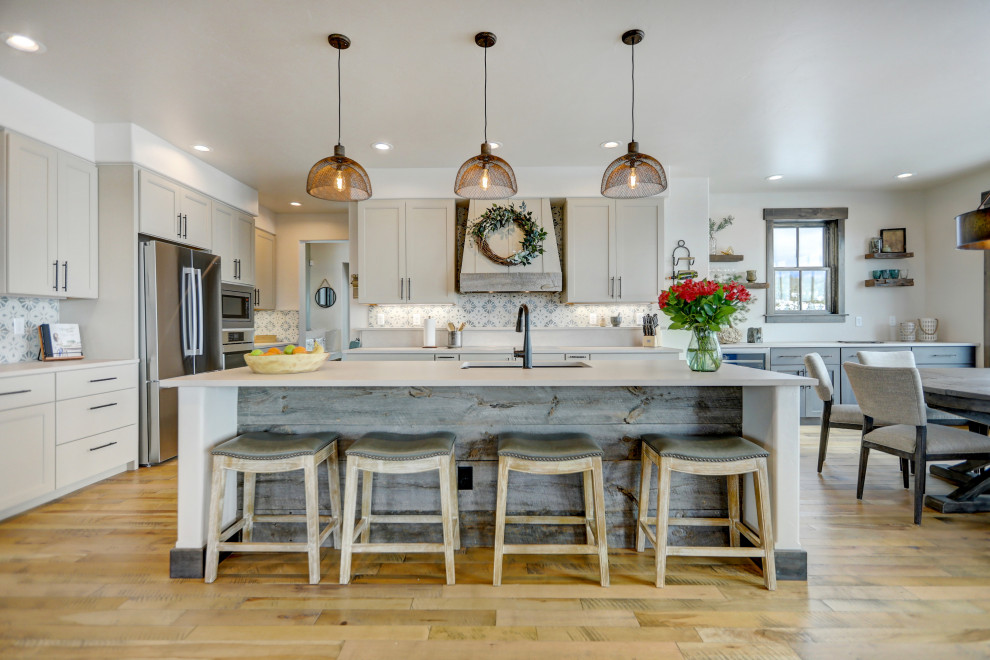 Design ideas for a large transitional eat-in kitchen in Denver with a single-bowl sink, shaker cabinets, beige cabinets, quartz benchtops, porcelain splashback, stainless steel appliances, medium hardwood floors, with island, brown floor and beige benchtop.