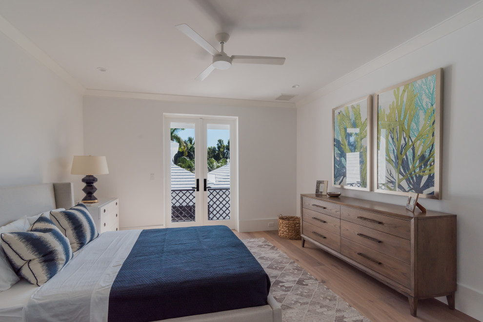Inspiration for a large beach style master bedroom in Miami with white walls, medium hardwood floors and beige floor.