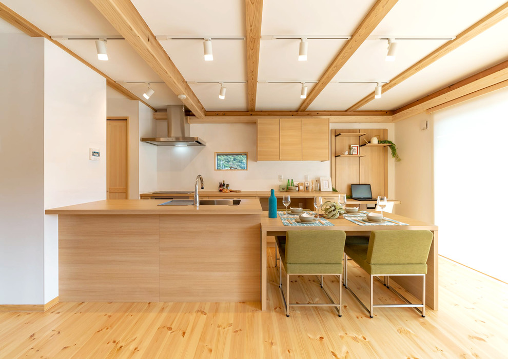 Design ideas for an asian galley eat-in kitchen with a peninsula, white splashback, stainless steel appliances, a drop-in sink, flat-panel cabinets, light wood cabinets, wood benchtops, light hardwood floors, beige floor and beige benchtop.
