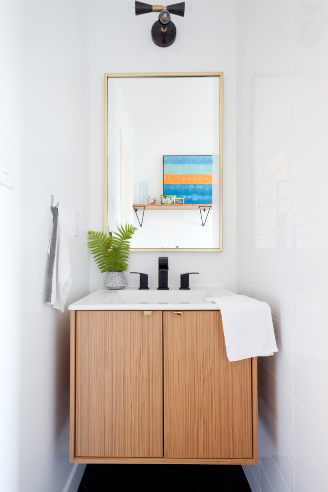 Photo of a contemporary powder room in Los Angeles with an integrated sink, flat-panel cabinets, light wood cabinets and white walls.