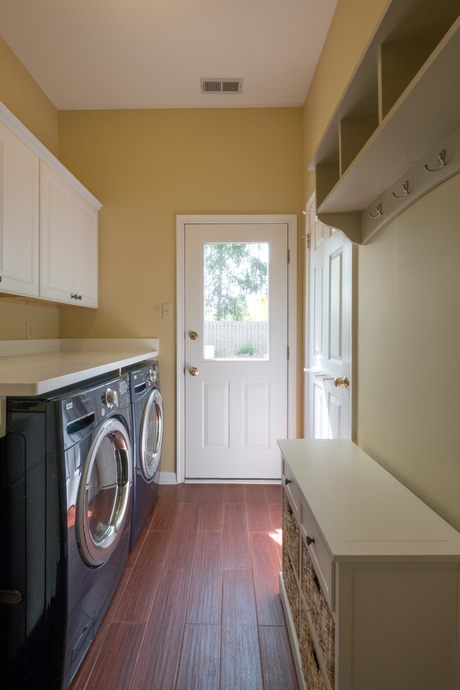 Inspiration for a mid-sized traditional galley utility room in Philadelphia with an undermount sink, recessed-panel cabinets, white cabinets, yellow walls, medium hardwood floors, a side-by-side washer and dryer and brown floor.