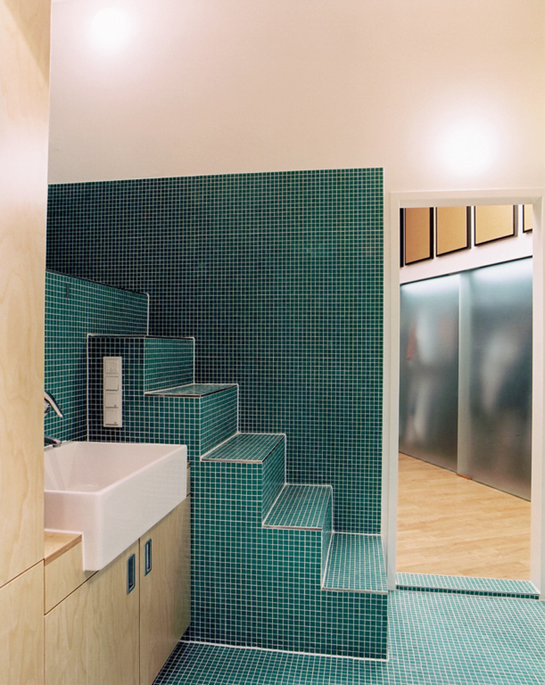 Photo of a mid-sized mediterranean bathroom in Berlin with flat-panel cabinets, light wood cabinets, green tile, white walls, mosaic tile floors, a vessel sink, wood benchtops and green floor.