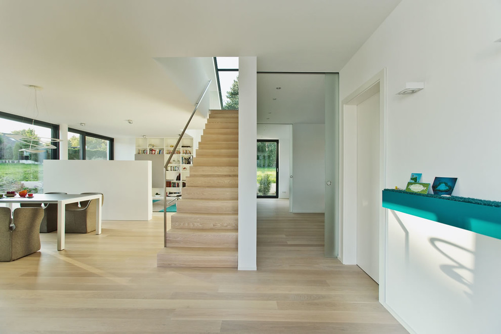 Photo of a large contemporary hallway in Cologne with white walls and medium hardwood floors.