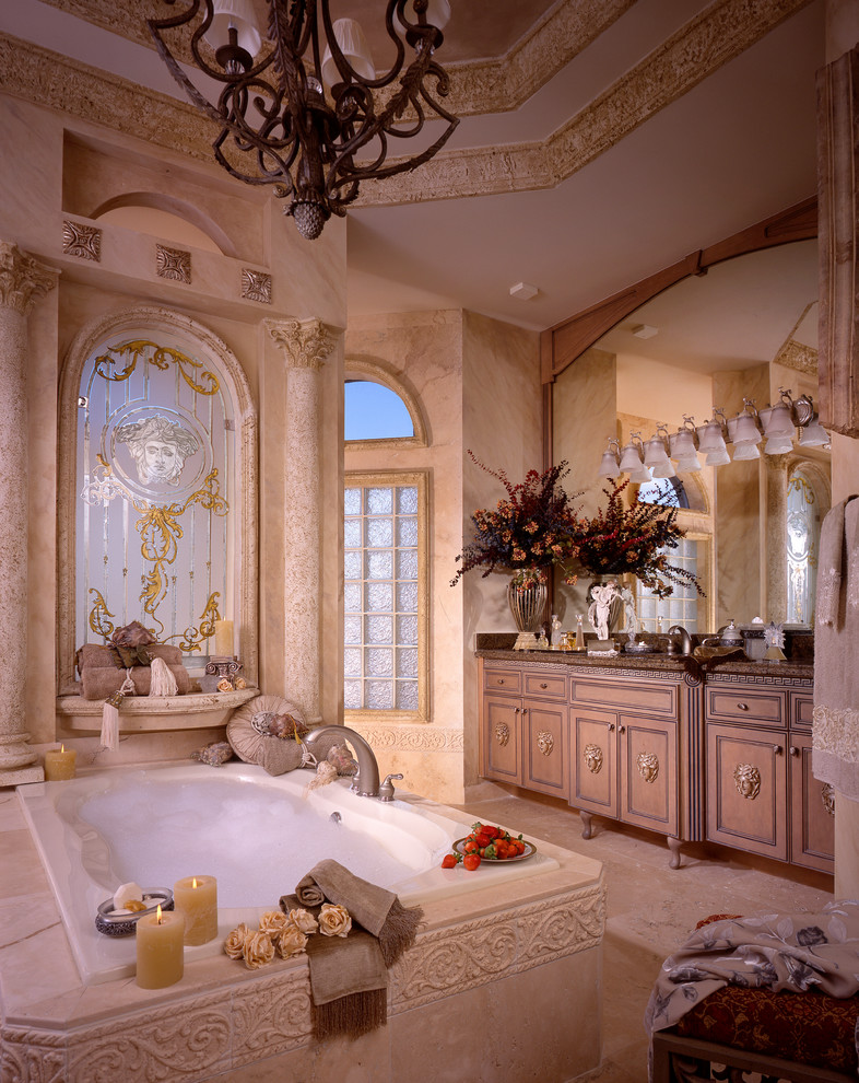Design ideas for a large mediterranean master bathroom in Miami with recessed-panel cabinets, beige cabinets, beige walls, marble floors, a drop-in tub and an undermount sink.