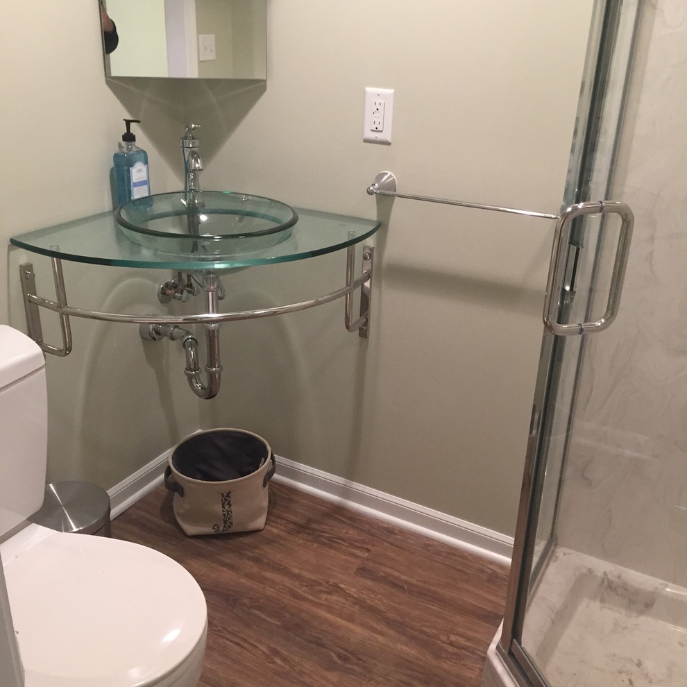 This is an example of a small transitional 3/4 bathroom in Kansas City with a corner shower, green walls, vinyl floors, a wall-mount sink and glass benchtops.