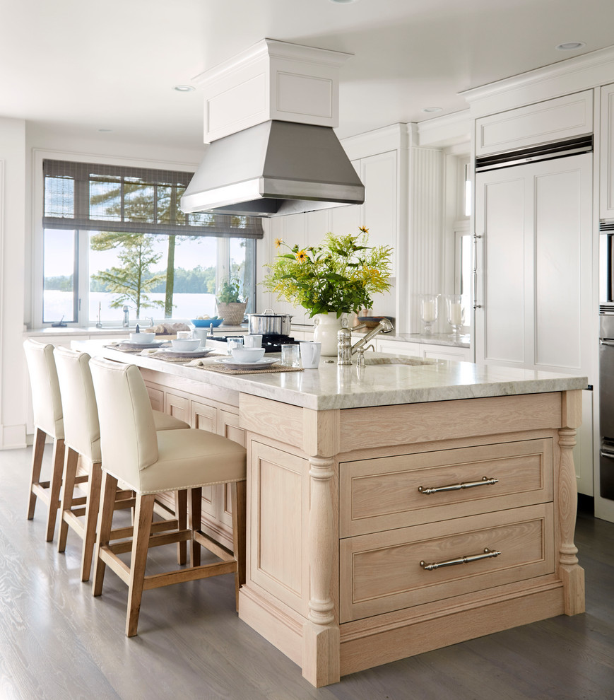 Large beach style l-shaped kitchen in Portland Maine with recessed-panel cabinets, with island, an undermount sink, white cabinets, medium hardwood floors, brown floor and white benchtop.