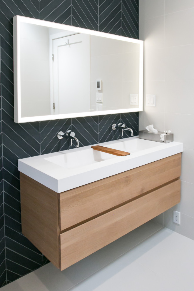 Inspiration for a small contemporary bathroom in Seattle with light wood cabinets, an alcove tub, a shower/bathtub combo, a wall-mount toilet, black tile, black walls, porcelain floors, a trough sink, white floor, white benchtops, a double vanity, porcelain tile, engineered quartz benchtops, a hinged shower door and a floating vanity.