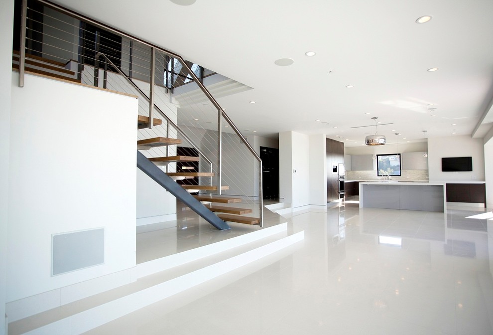 Expansive contemporary wood l-shaped staircase in Los Angeles with open risers and cable railing.