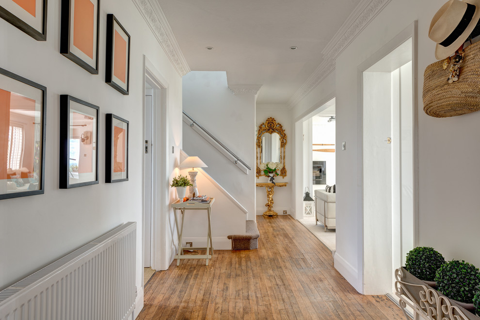 Photo of a mid-sized beach style hallway in Devon with white walls and medium hardwood floors.