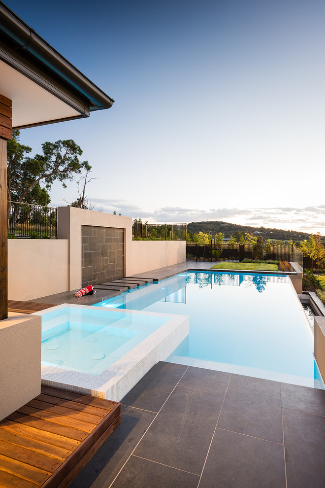 Photo of a large contemporary rectangular infinity pool in Melbourne with a hot tub and tile.