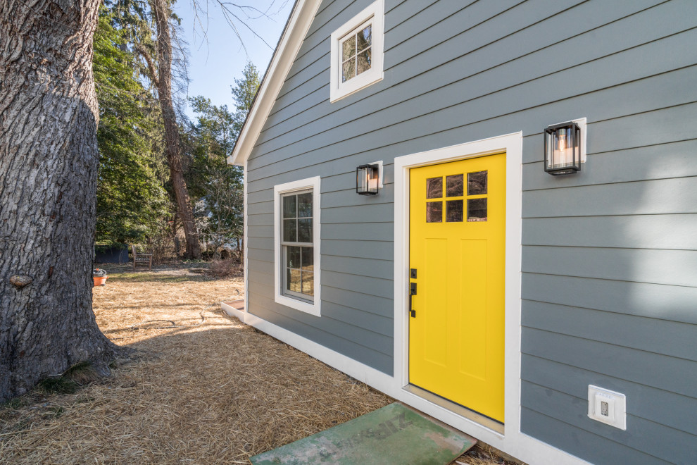 Immagine della micro casa blu classica con rivestimento con lastre in cemento, tetto a capanna, copertura a scandole e pannelli sovrapposti