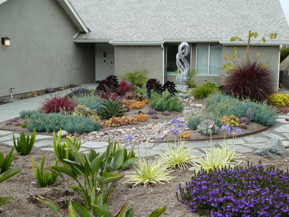 This is an example of a transitional front yard full sun xeriscape in San Diego with a garden path and natural stone pavers.
