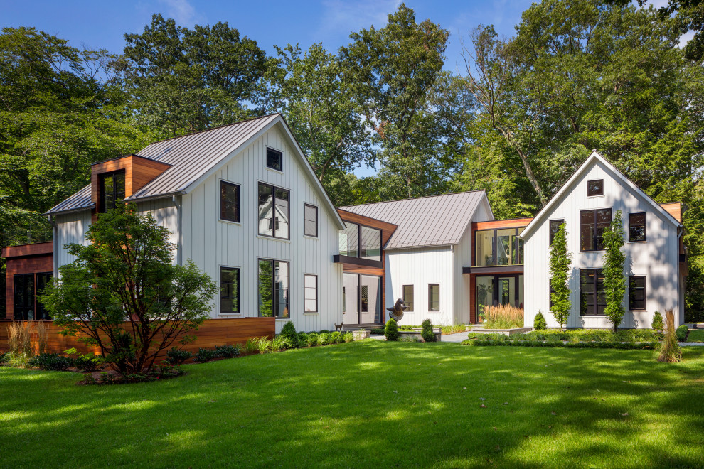 Idée de décoration pour une façade de maison blanche champêtre en bois et bardage à clin à un étage avec un toit à deux pans, un toit en métal et un toit gris.