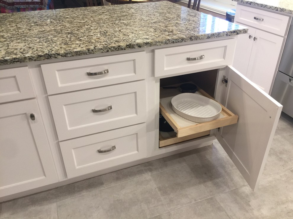 Inspiration for a mid-sized transitional l-shaped porcelain tile eat-in kitchen remodel in Austin with an undermount sink, shaker cabinets, white cabinets, granite countertops, white backsplash, glass tile backsplash, stainless steel appliances and an island