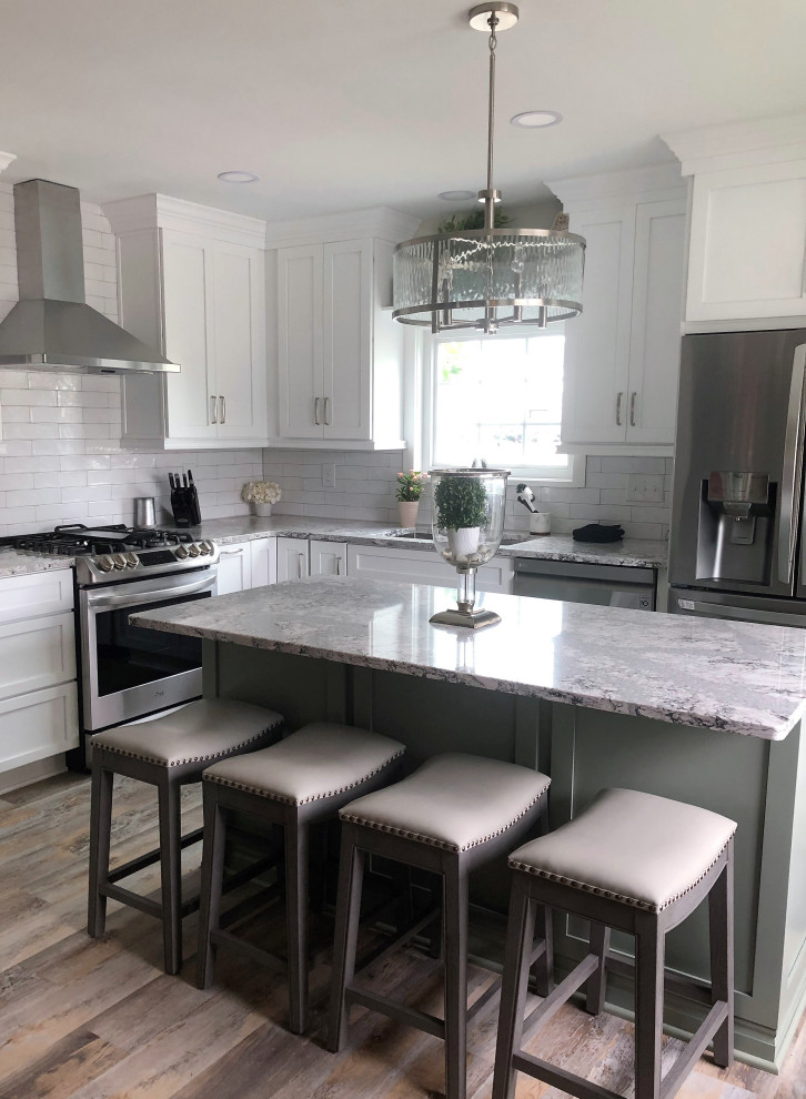 Eat-in kitchen - mid-sized transitional l-shaped vinyl floor and multicolored floor eat-in kitchen idea with an undermount sink, flat-panel cabinets, green cabinets, quartz countertops, white backsplash, ceramic backsplash, stainless steel appliances, an island and gray countertops