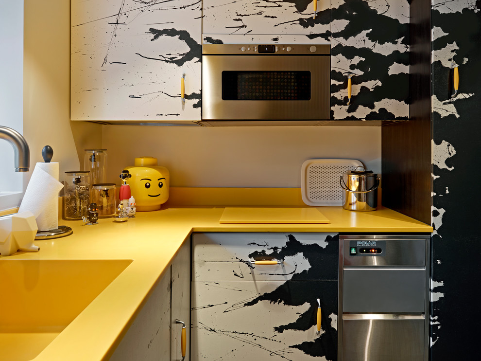 Photo of an eclectic l-shaped separate kitchen in London with flat-panel cabinets, stainless steel appliances, an integrated sink, yellow splashback, no island and yellow benchtop.