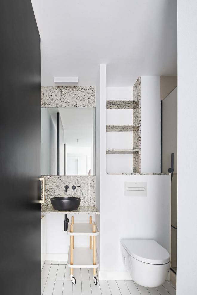 Inspiration for a contemporary powder room in Barcelona with open cabinets, a wall-mount toilet, white walls, a vessel sink and white floor.