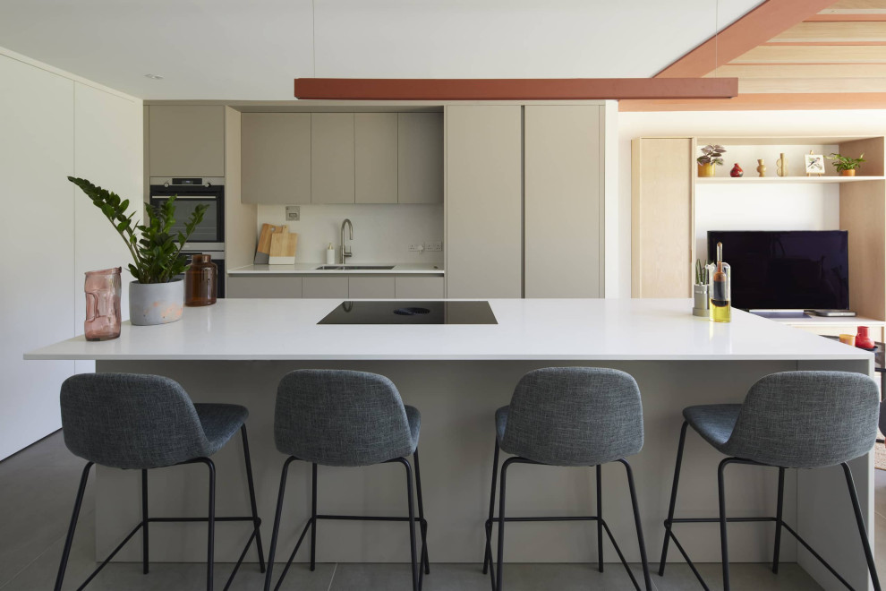 This is an example of a small contemporary galley open plan kitchen in London with a double-bowl sink, beige cabinets, quartz worktops, beige splashback, stainless steel appliances, ceramic flooring, an island, grey floors, white worktops, feature lighting and flat-panel cabinets.