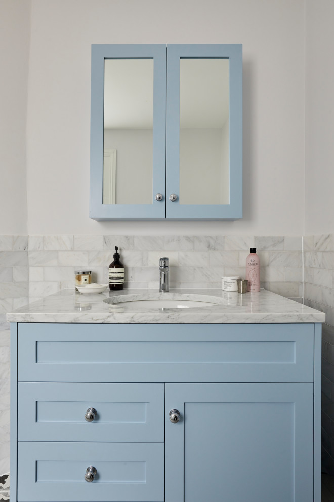 Photo of a large contemporary kids bathroom in London with blue cabinets, a drop-in tub, an open shower, a two-piece toilet, gray tile, an integrated sink, marble benchtops, a hinged shower door, a single vanity and a freestanding vanity.