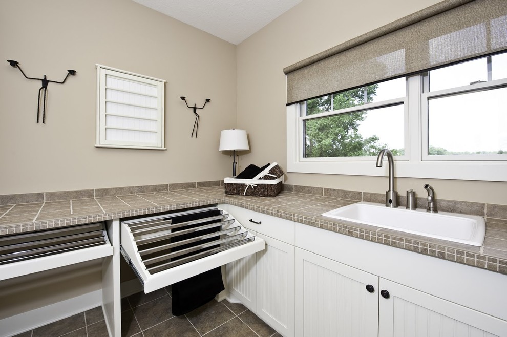 Photo of a large arts and crafts laundry room in Grand Rapids with a drop-in sink, recessed-panel cabinets, white cabinets, limestone benchtops, beige walls and slate floors.