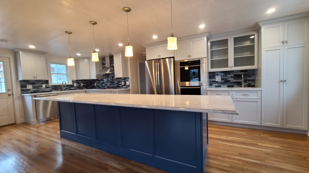 This is an example of a large modern l-shaped eat-in kitchen in Boston with an undermount sink, shaker cabinets, grey cabinets, quartz benchtops, blue splashback, porcelain splashback, stainless steel appliances, medium hardwood floors, with island and white benchtop.