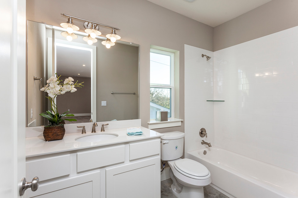 Photo of a mid-sized country kids bathroom in Austin with recessed-panel cabinets, white cabinets, a freestanding tub, a curbless shower, a one-piece toilet, gray tile, porcelain tile, grey walls, plywood floors, an undermount sink and solid surface benchtops.