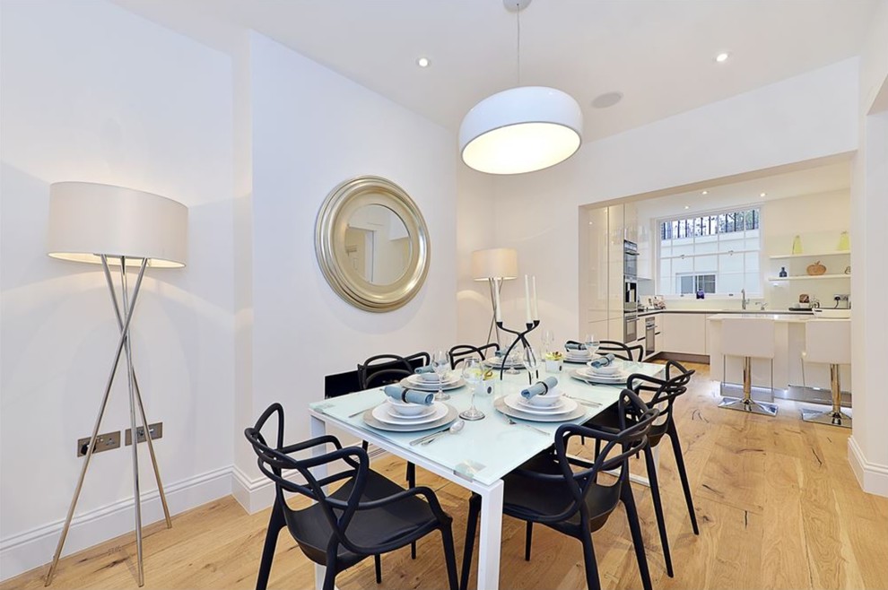 Large contemporary kitchen/dining combo in London with white walls, light hardwood floors and beige floor.