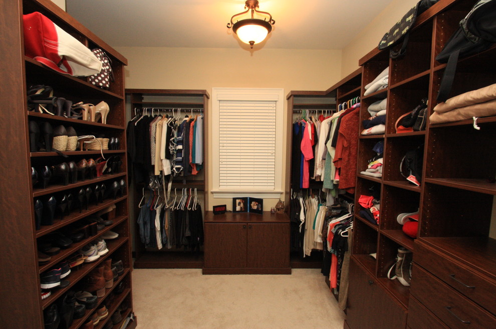 Inspiration for a large traditional gender-neutral walk-in wardrobe in Raleigh with flat-panel cabinets, dark wood cabinets, carpet and beige floor.