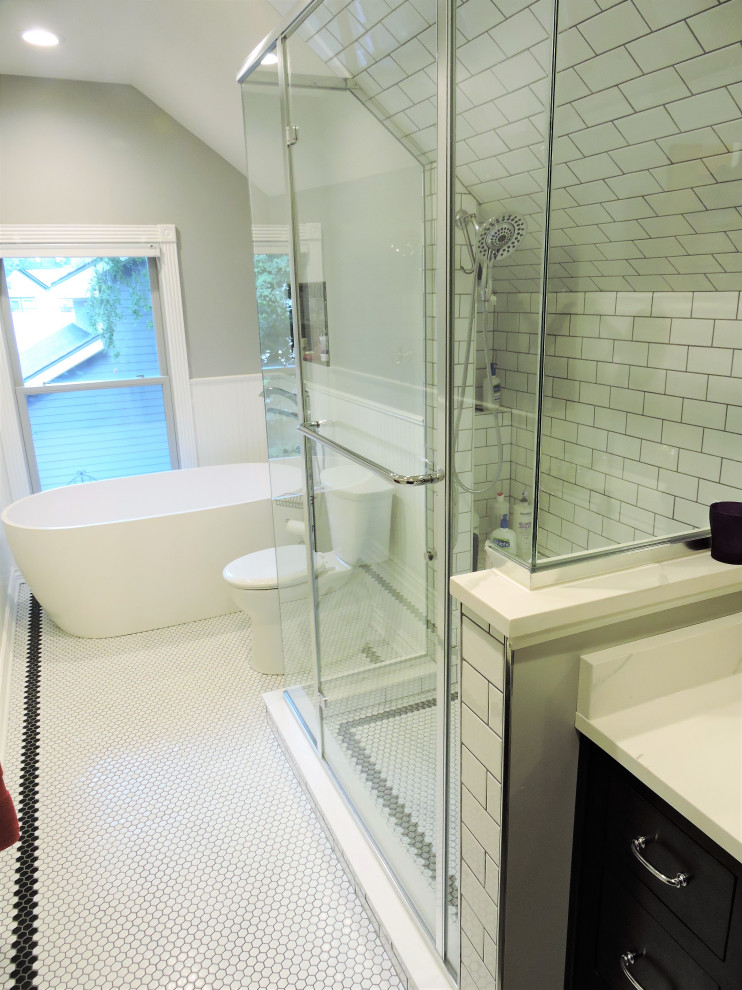 Photo of a small traditional master bathroom in Other with an alcove shower, a two-piece toilet, a hinged shower door, a single vanity, black cabinets, a freestanding tub, white tile, ceramic tile, grey walls, ceramic floors, an undermount sink, quartzite benchtops, white floor, white benchtops, a shower seat, a built-in vanity, decorative wall panelling and recessed-panel cabinets.