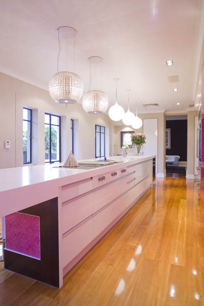 Inspiration for a large modern galley kitchen in Los Angeles with an undermount sink, flat-panel cabinets, white cabinets, quartz benchtops, pink splashback, glass sheet splashback, stainless steel appliances, light hardwood floors and with island.
