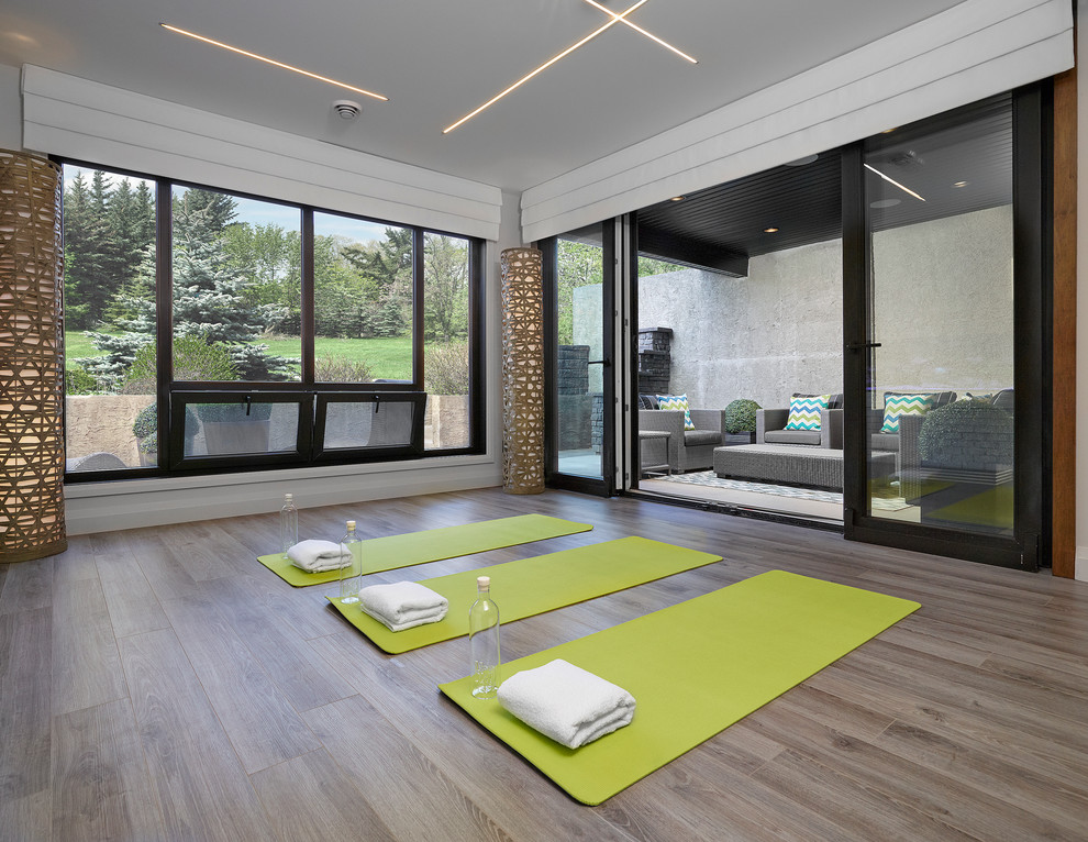 This is an example of a mid-sized contemporary home yoga studio in Edmonton with grey walls and light hardwood floors.