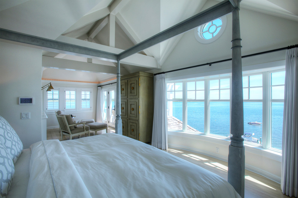Design ideas for a large beach style master bedroom in Orange County with white walls and light hardwood floors.