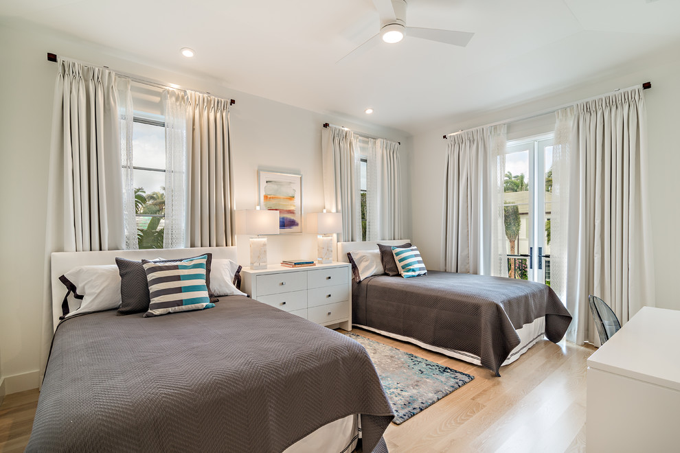 Photo of a transitional guest bedroom in Miami with white walls, light hardwood floors and beige floor.