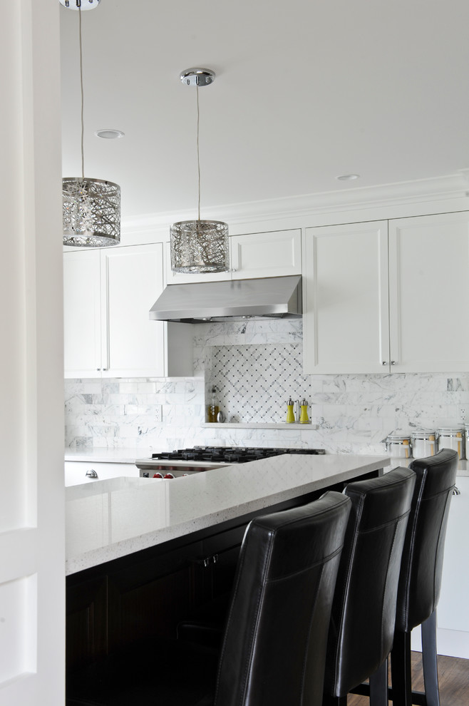 This is an example of a transitional l-shaped open plan kitchen in Vancouver with an undermount sink, shaker cabinets, white cabinets, quartz benchtops, white splashback, stone tile splashback and stainless steel appliances.