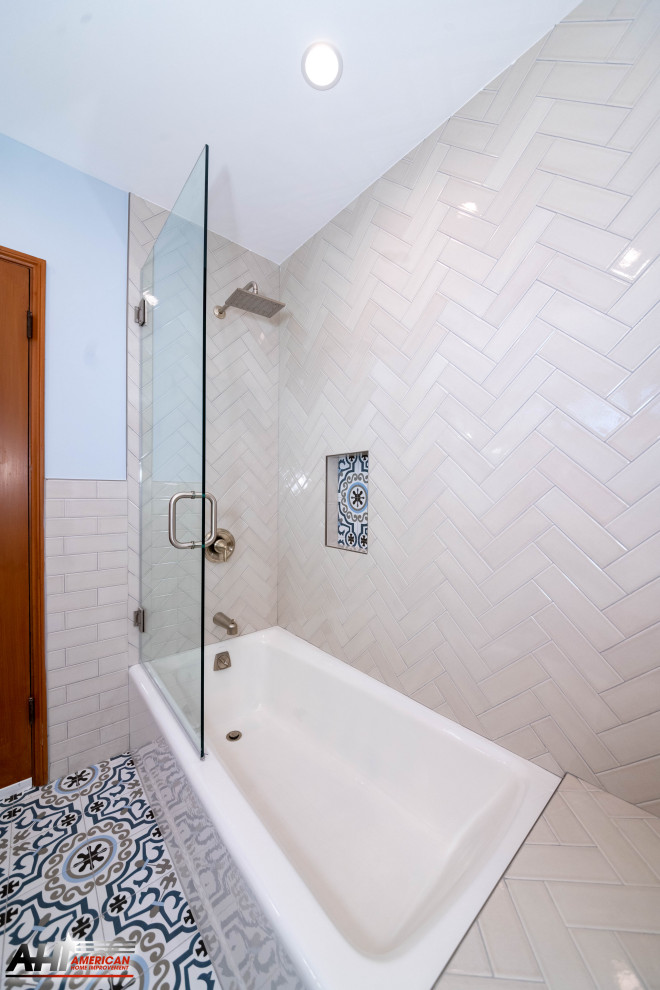 На фото: ванная комната среднего размера в стиле модернизм с фасадами с выступающей филенкой, серыми фасадами, угловой ванной, душем над ванной, унитазом-моноблоком, белой плиткой, плиткой кабанчик, белыми стенами, полом из цементной плитки, душевой кабиной, врезной раковиной, столешницей из кварцита, разноцветным полом, душем с распашными дверями, белой столешницей, нишей, тумбой под одну раковину и встроенной тумбой