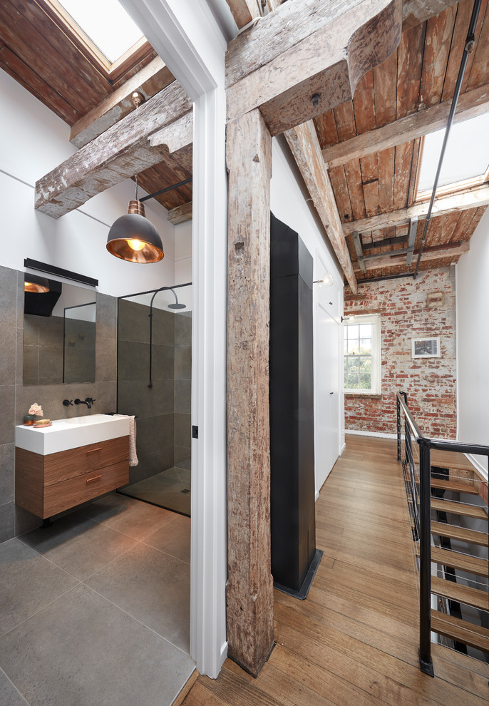 This is an example of a small industrial 3/4 bathroom in Melbourne with flat-panel cabinets, dark wood cabinets, an open shower, a one-piece toilet, gray tile, porcelain tile, porcelain floors, an integrated sink, solid surface benchtops, grey floor and an open shower.