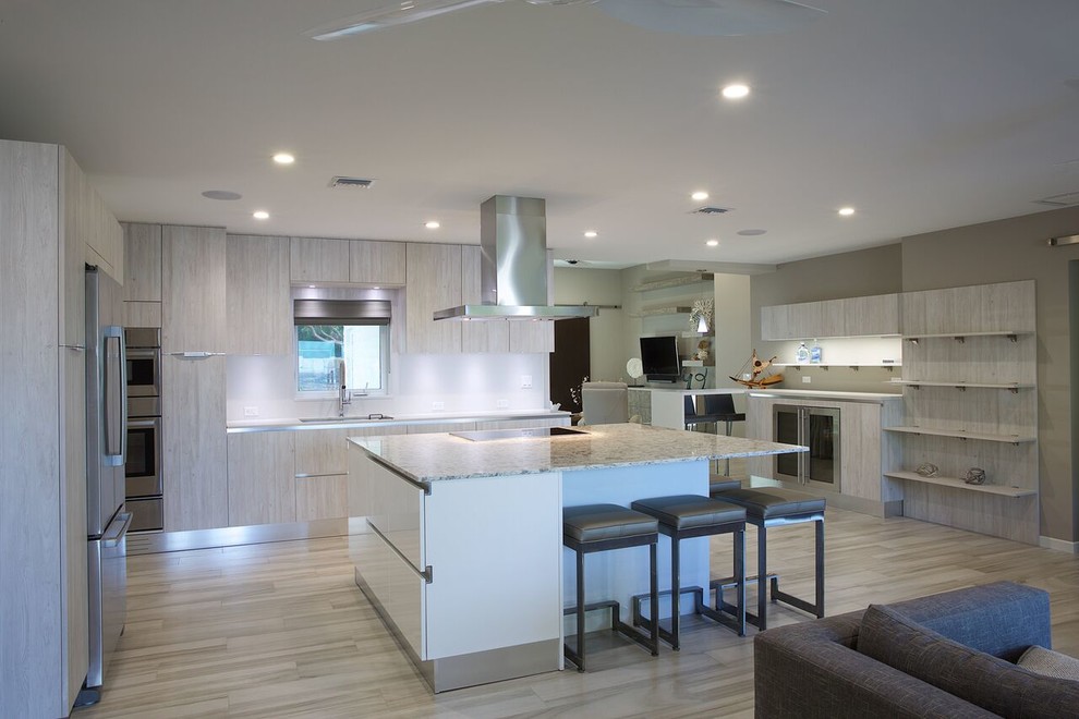 Photo of a mid-sized tropical eat-in kitchen in Miami with a single-bowl sink, flat-panel cabinets, light wood cabinets, quartz benchtops, stainless steel appliances, porcelain floors and with island.