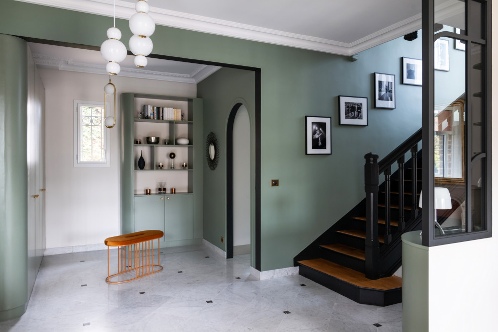 Modern inredning av en stor foajé, med gröna väggar, marmorgolv, en dubbeldörr, en svart dörr och vitt golv