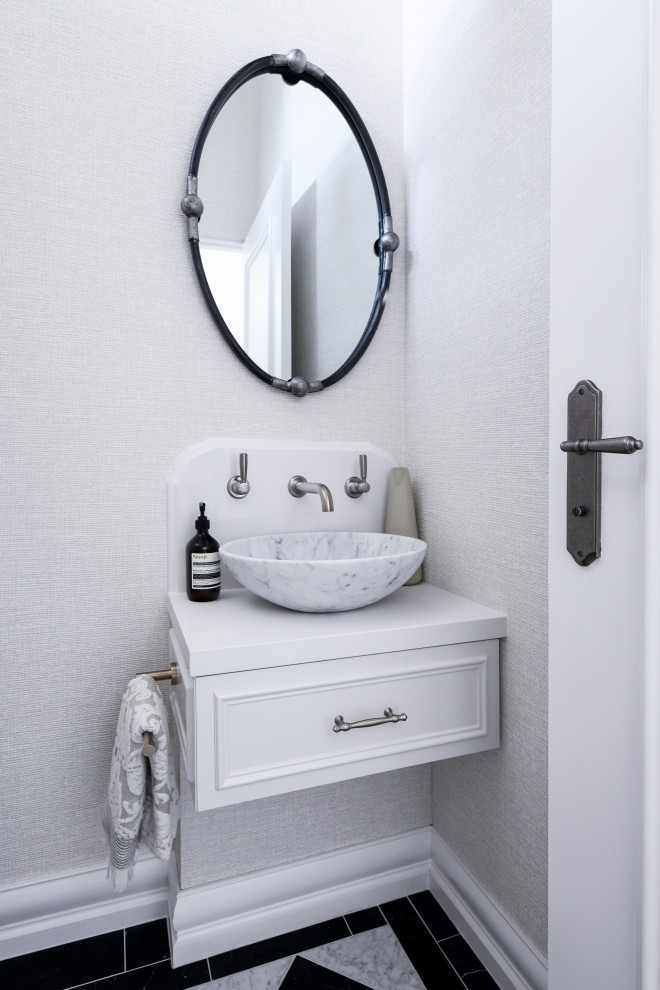 Photo of a mid-sized traditional powder room in Sydney with raised-panel cabinets, white cabinets, a one-piece toilet, beige walls, marble floors, a drop-in sink, engineered quartz benchtops, black floor, white benchtops, a floating vanity and wallpaper.