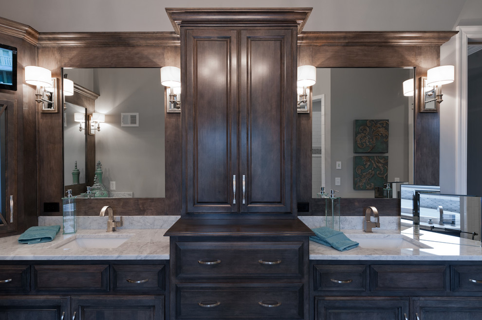 This is an example of a mid-sized transitional master wet room bathroom in Kansas City with shaker cabinets, brown cabinets, a drop-in tub, a two-piece toilet, beige tile, marble, grey walls, medium hardwood floors, an undermount sink, marble benchtops, grey floor and an open shower.