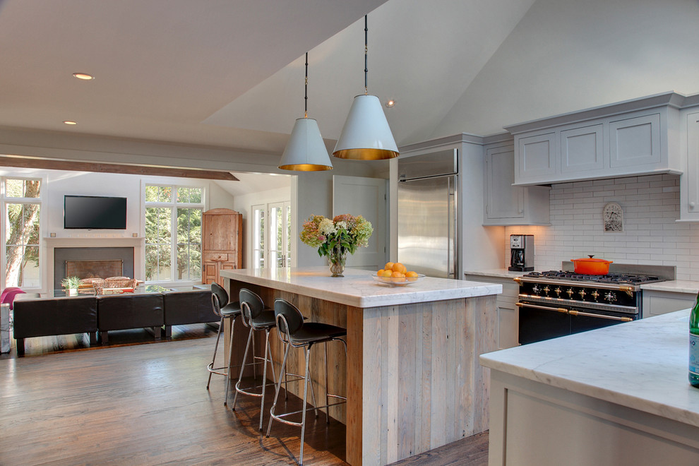 Mid-sized transitional l-shaped medium tone wood floor open concept kitchen photo in New York with an undermount sink, recessed-panel cabinets, gray cabinets, marble countertops, white backsplash, subway tile backsplash, stainless steel appliances and an island